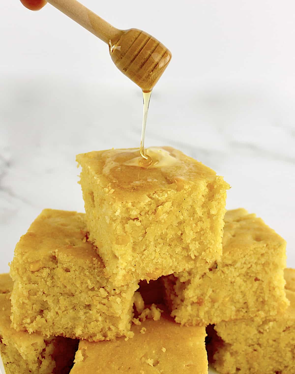 Gluten Free Cornbread slice with honey being drizzled over top