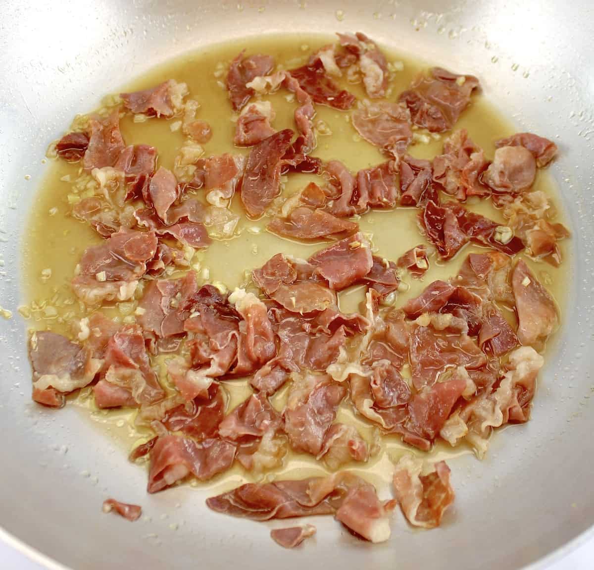 prosciutto being sauteed in skillet with vodka