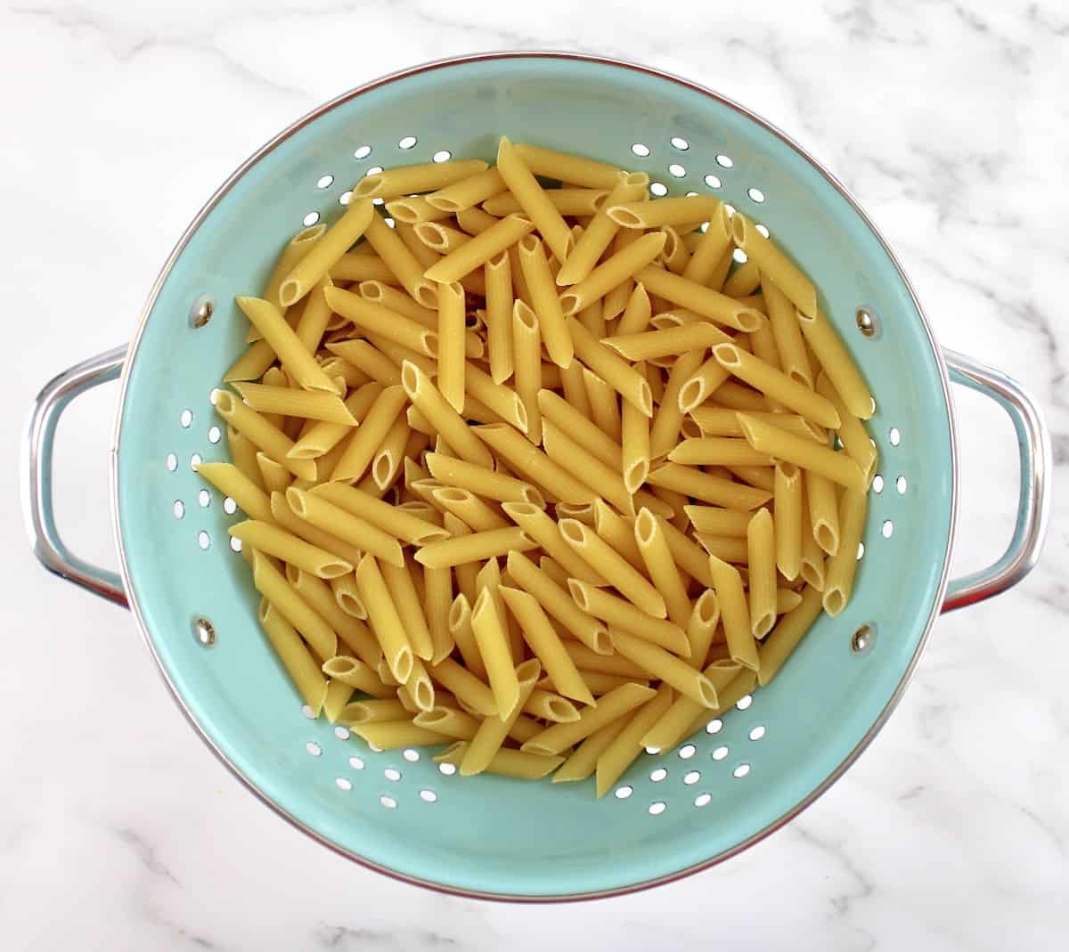 penne pasta in blue strainer