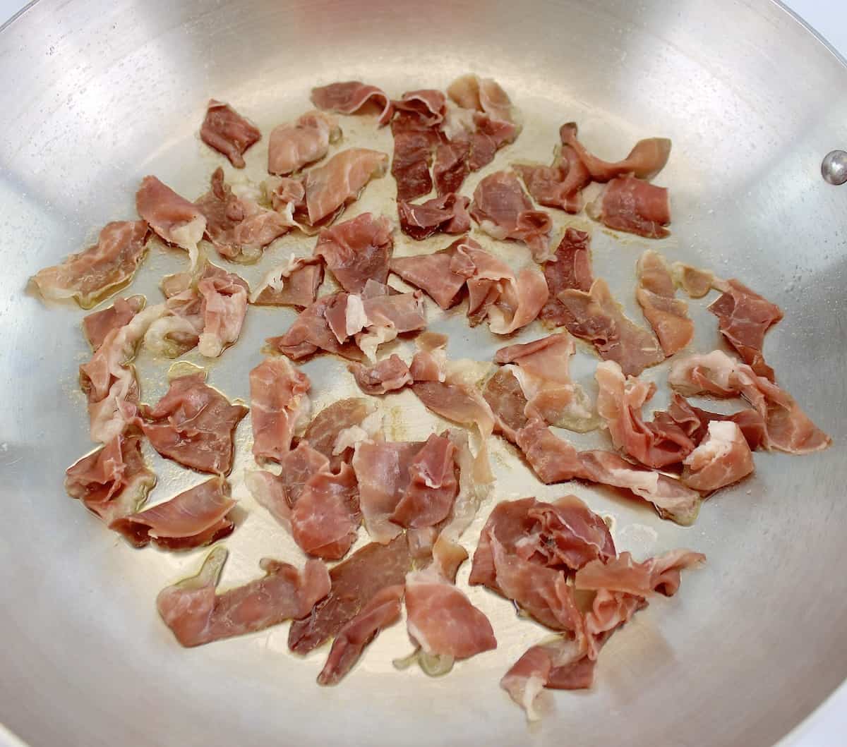 prosciutto being sauteed in skillet
