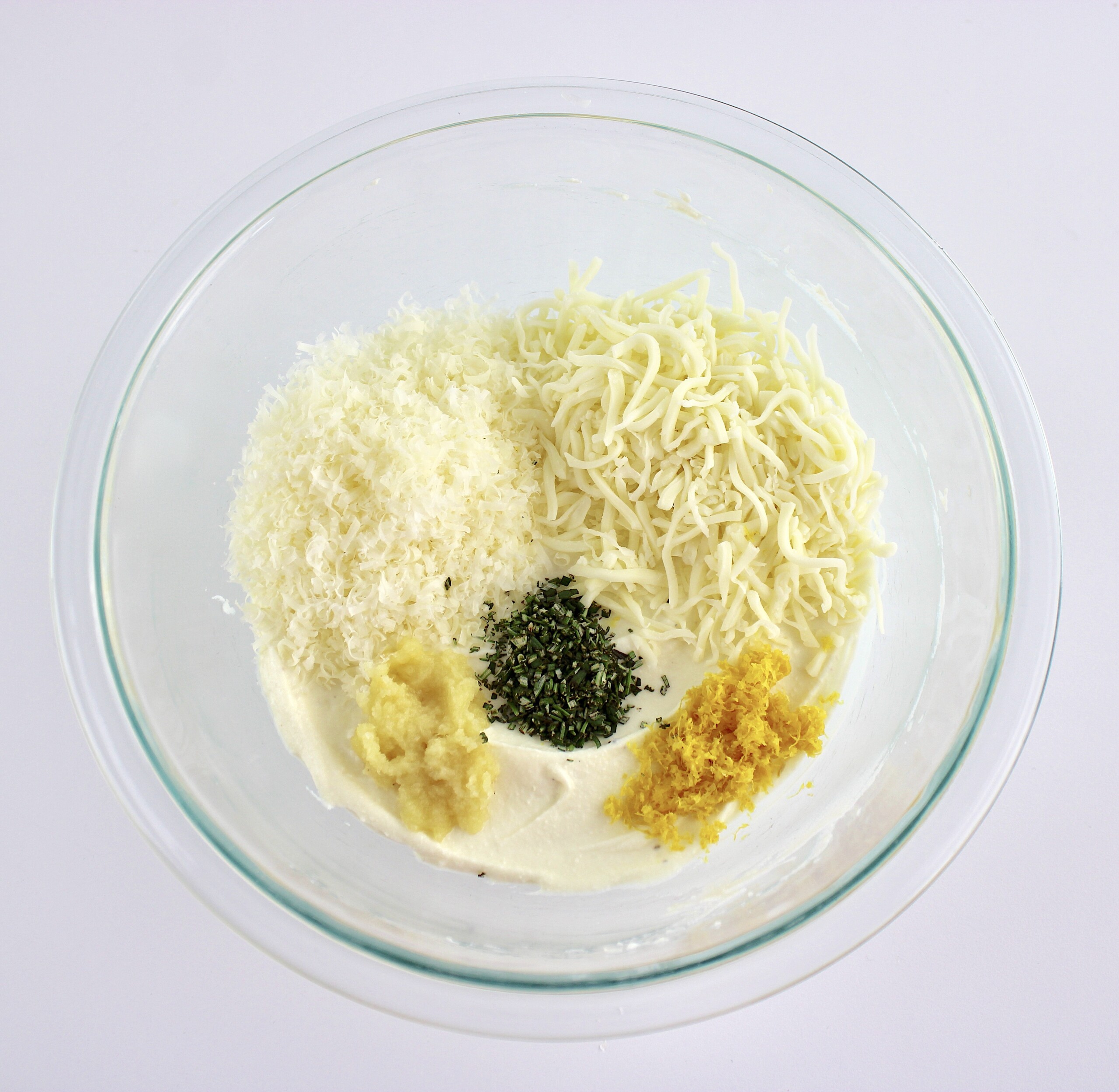 whipped ricotta with grated parmesan shredded mozzarella lemon zest garlic and rosemary in glass bowl