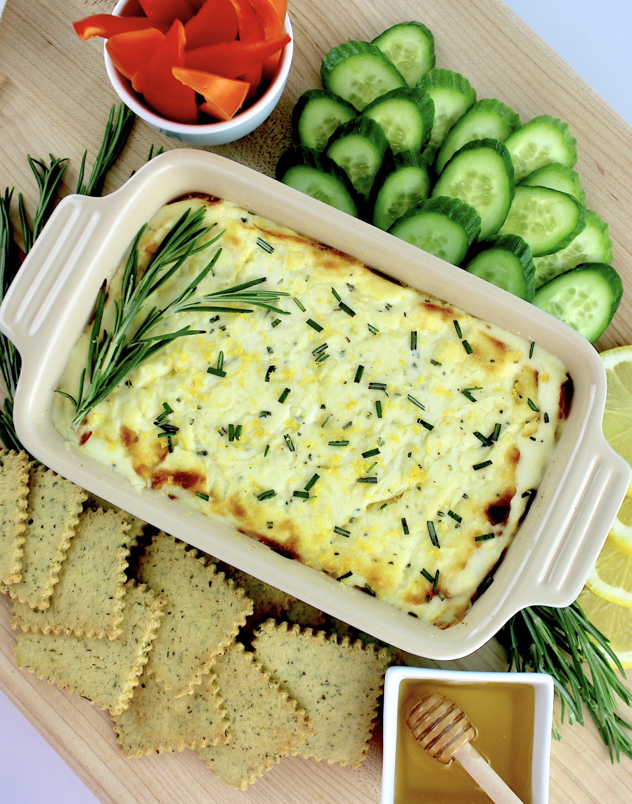 overhead view of Ricotta Dip with slices of cucumbers crackers and lemons on side