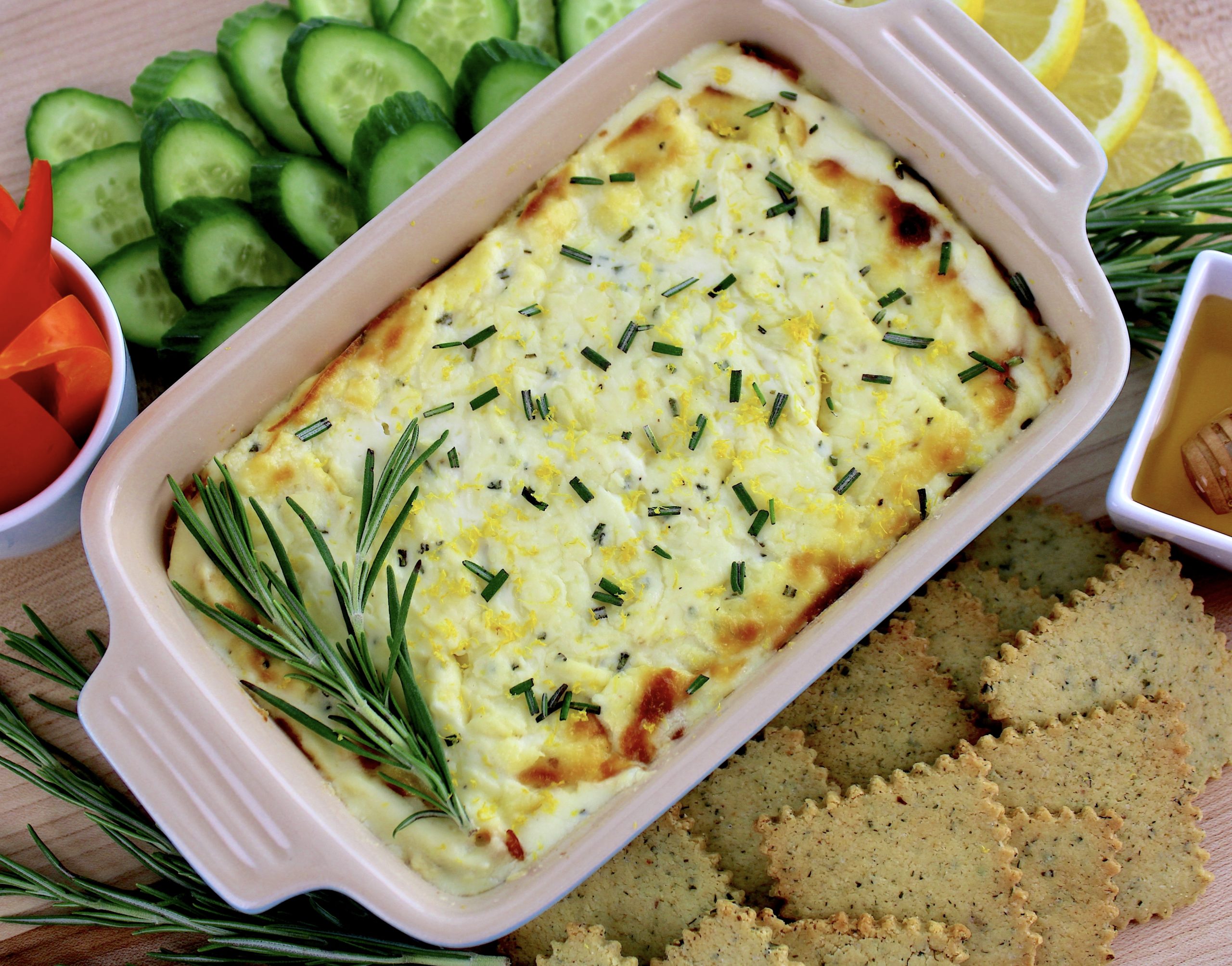 overhead view of Ricotta Dip with slices of cucumbers crackers and lemons on side