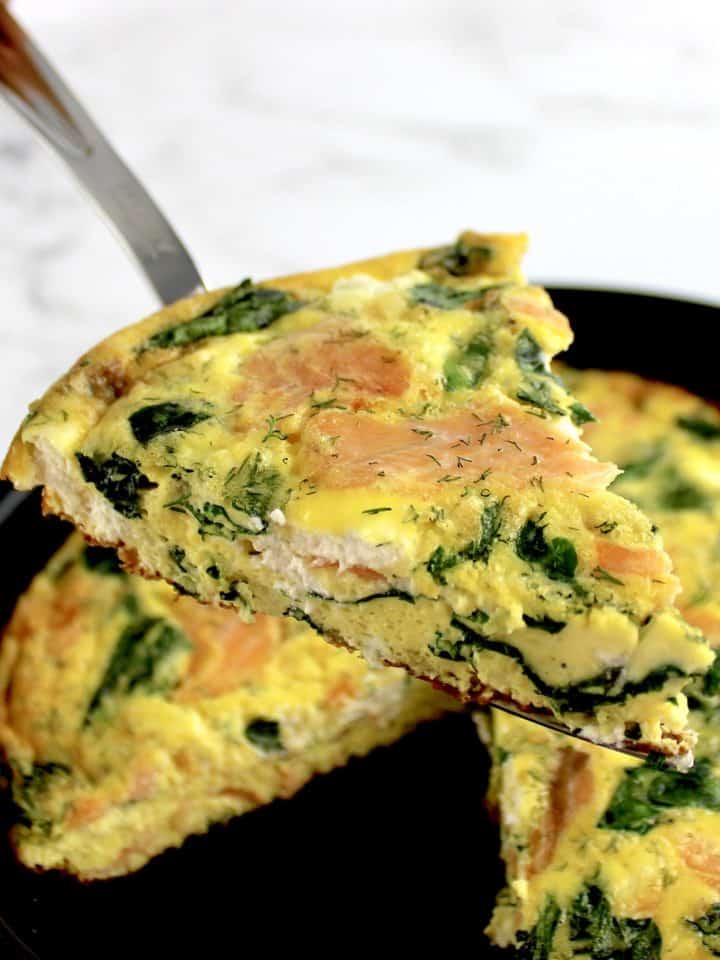 Smoked Salmon Frittata slice held up over skillet