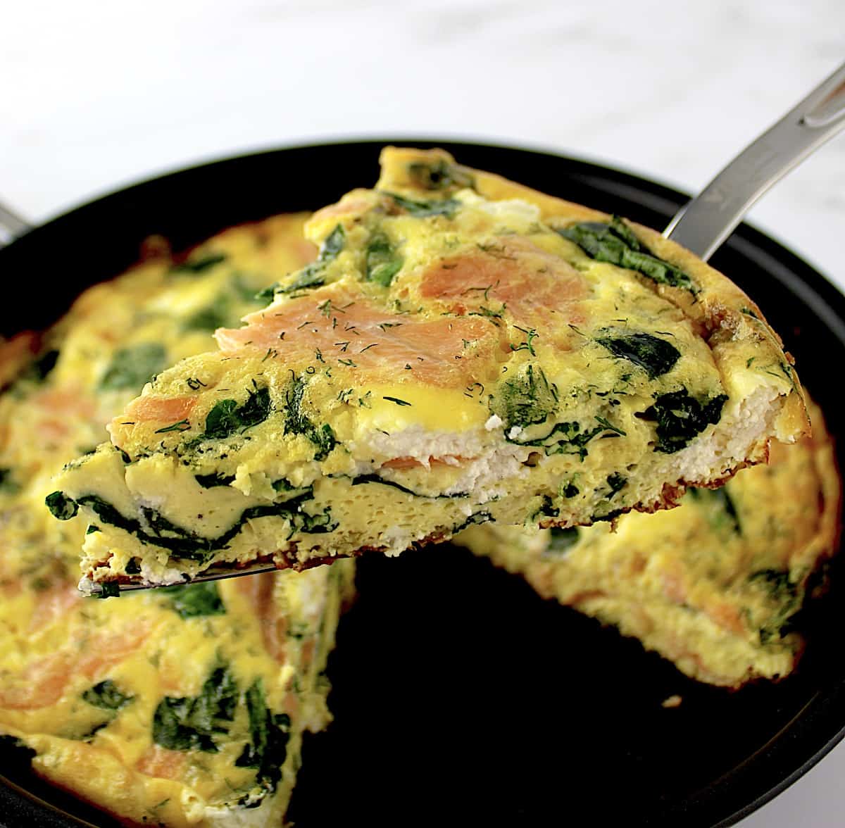 Smoked Salmon Frittata slice held up over skillet