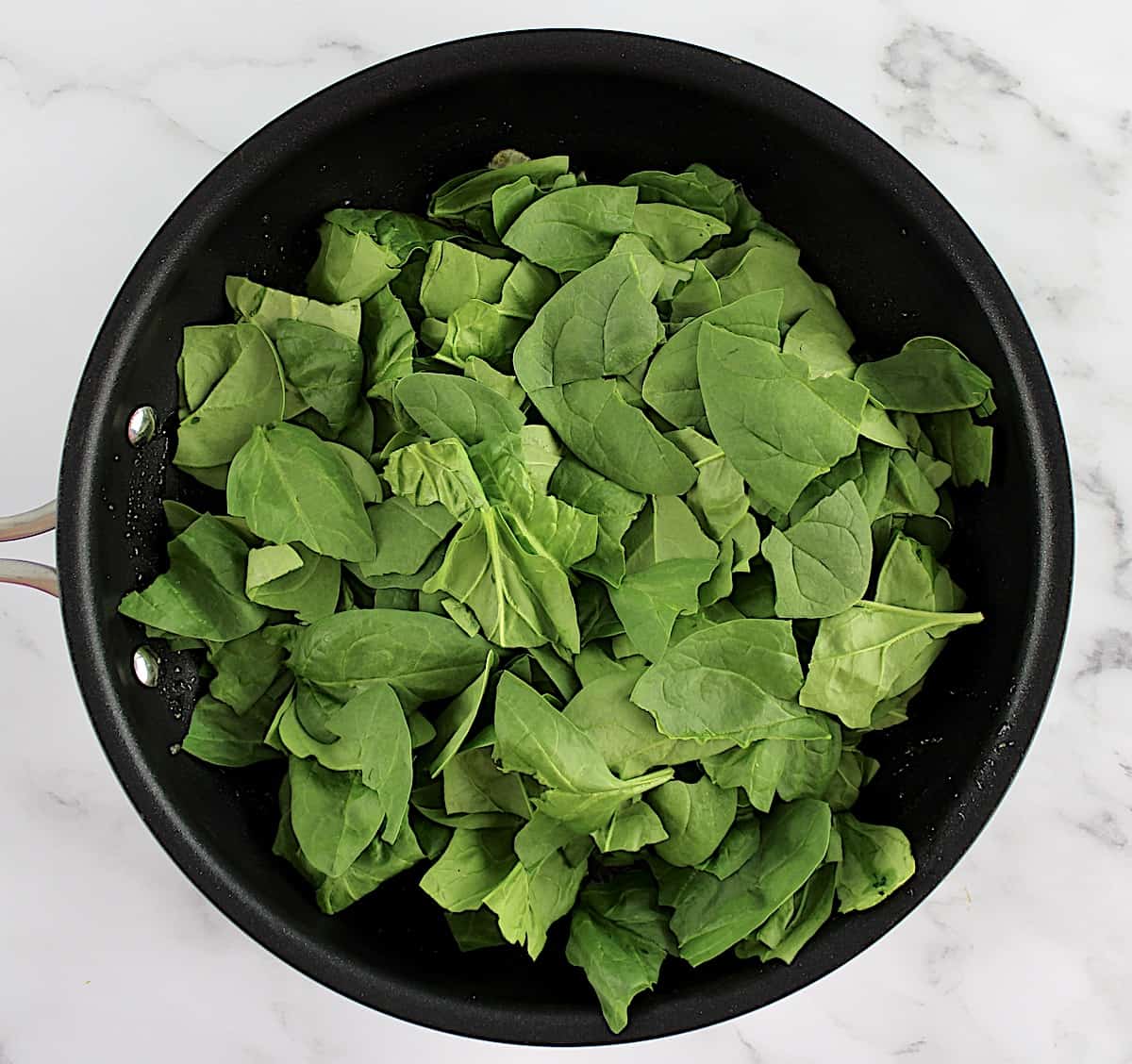 raw baby spinach in skillet