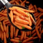 Air Fryer Baby Carrots in black serving spoon over air fryer basket