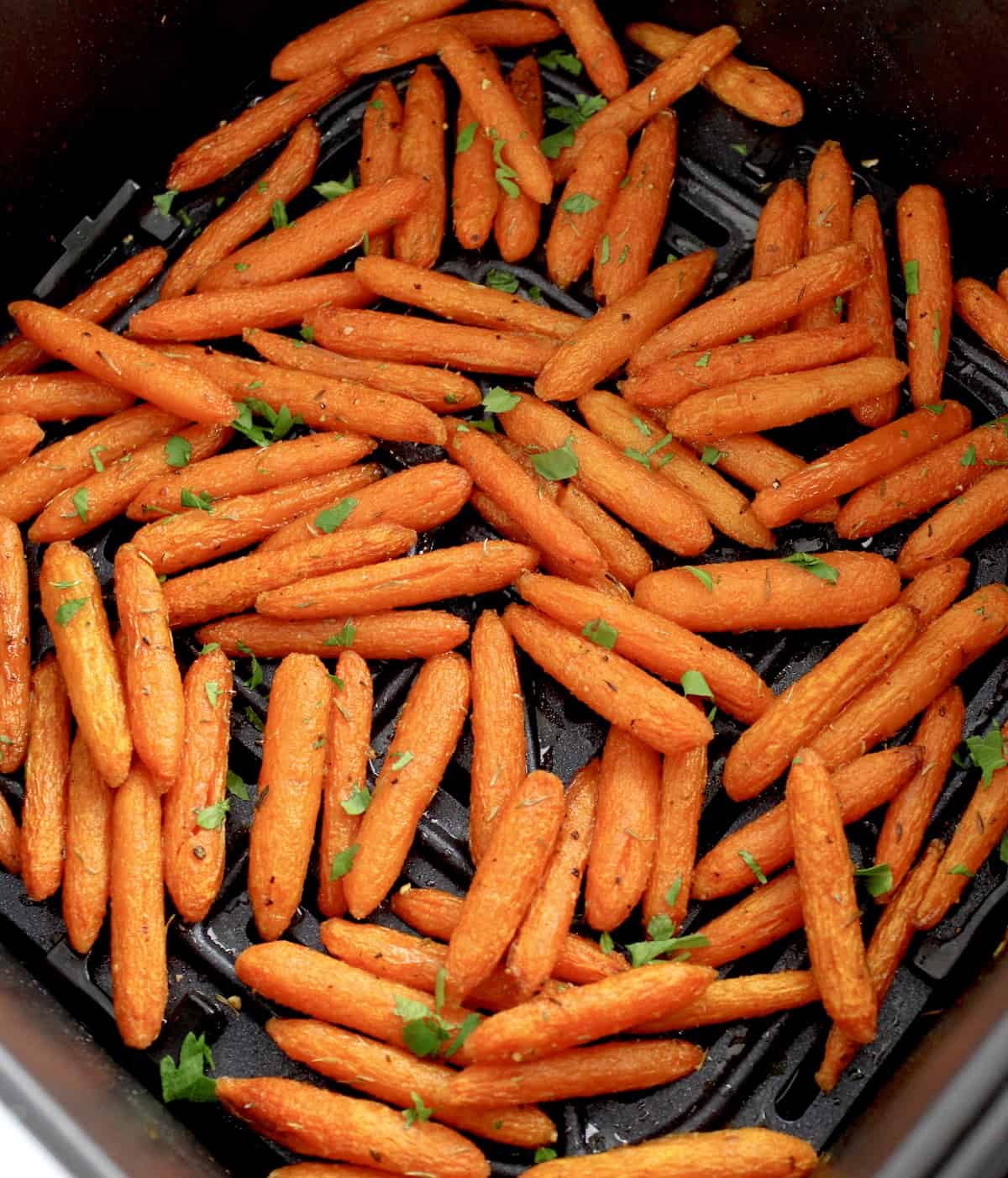 roasted air fryer baby carrots in air fryer basket with chopped parsley