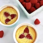 overhead view of 2 Baked Ricotta Raspberry Puddings with pint of raspberries in back