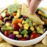 Cowboy Caviar in white bowl with tortilla chip dipping in