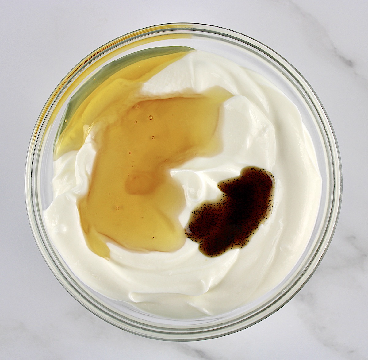 yogurt, vanilla and honey in glass bowl unmixed