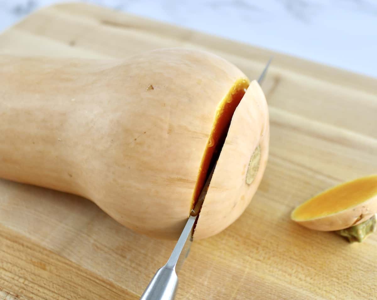 knife cutting the end off butternut squash on cutting board