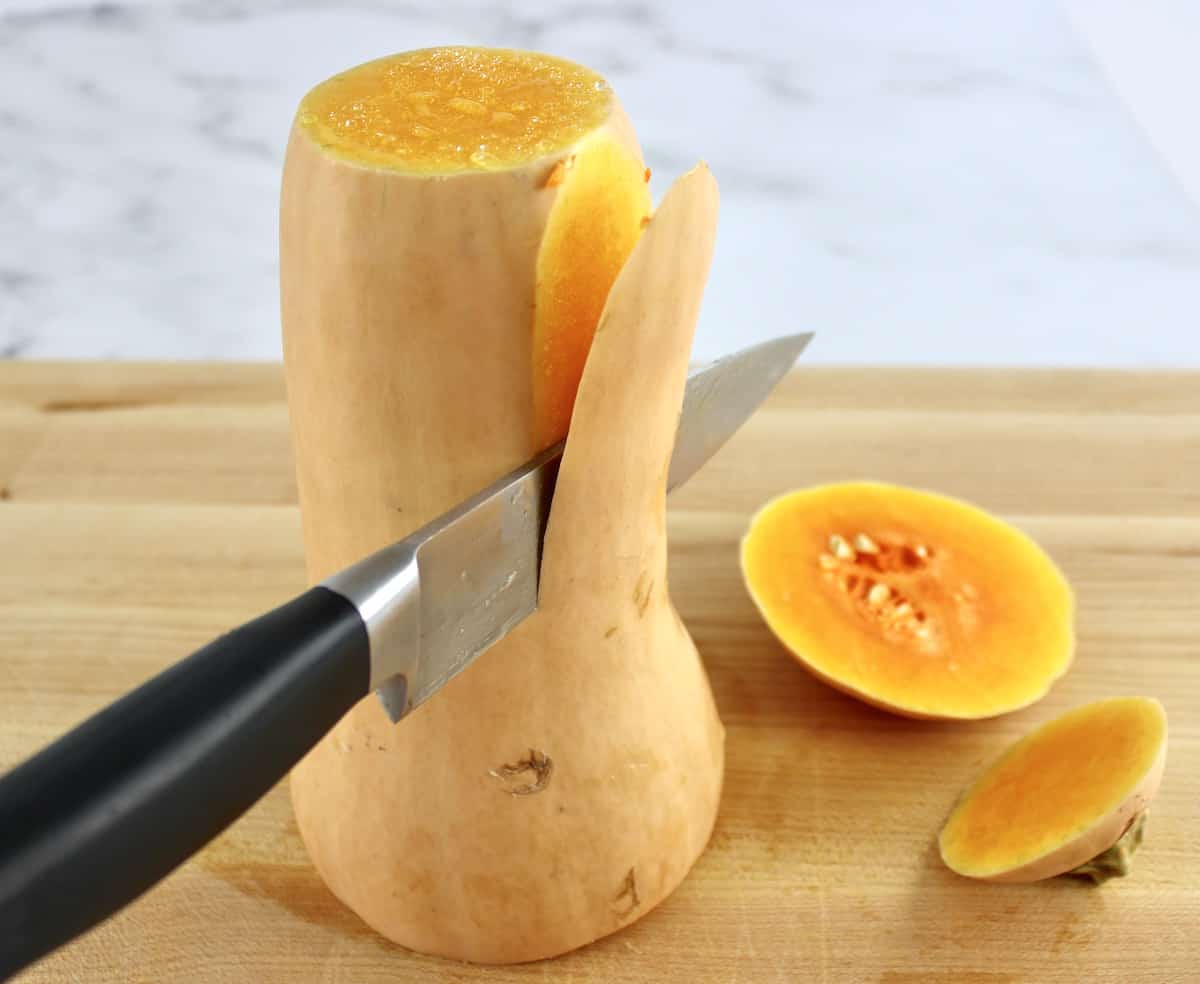 knife slicing the peel off butternut squash on cutting board
