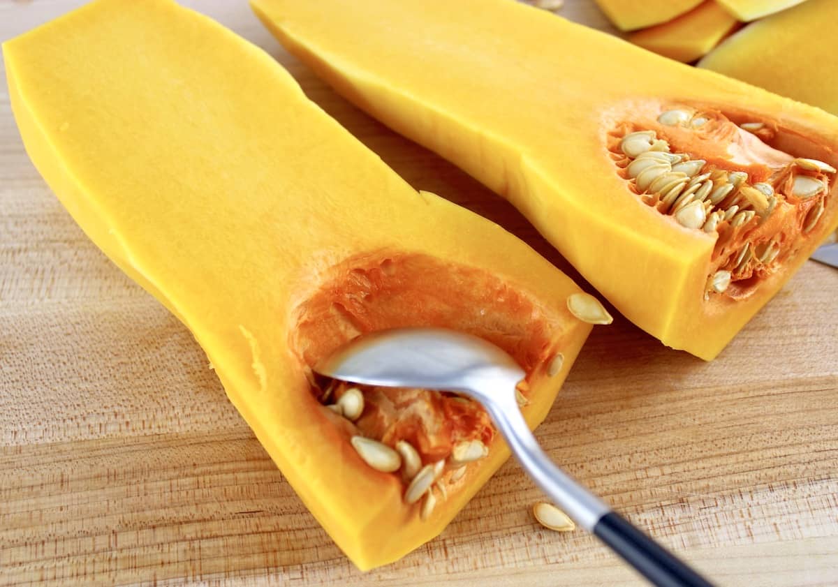 spoon scooping out seeds and pulp in butternut squash