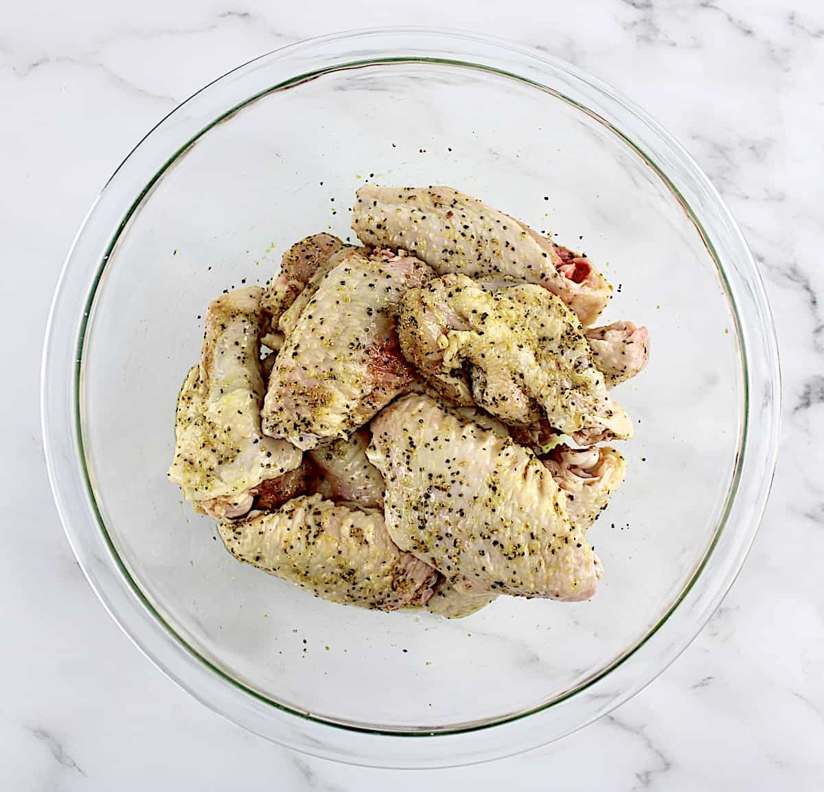 uncooked lemon pepper wings in glass bowl