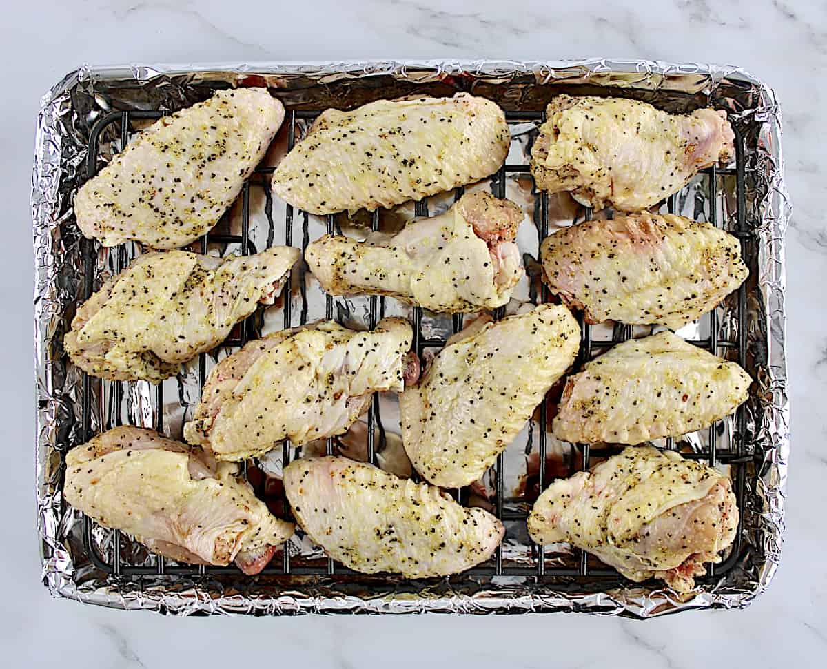 raw lemon pepper wings on wire rack lined with foil