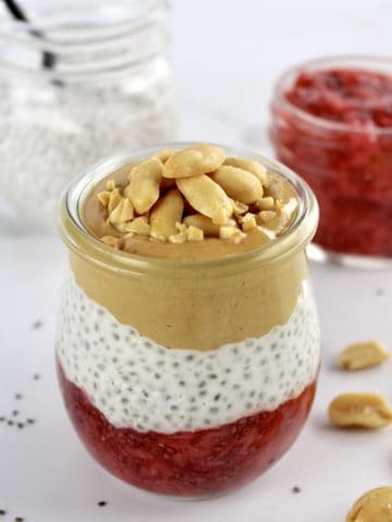 Peanut butter and Jelly Chia Pudding layered in glass jar with peanuts on top