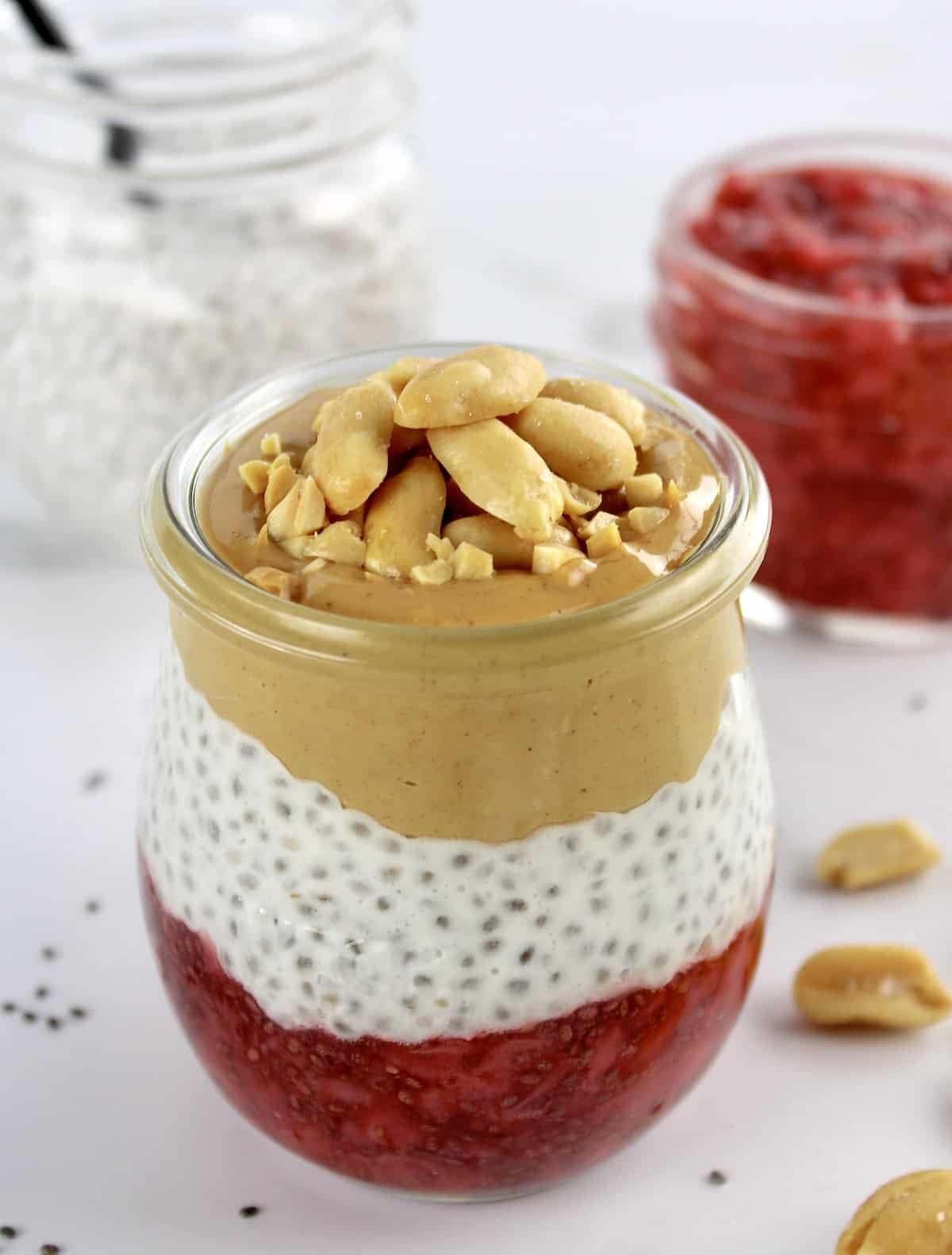 Peanut butter and Jelly Chia Pudding layered in glass jar with peanuts on top