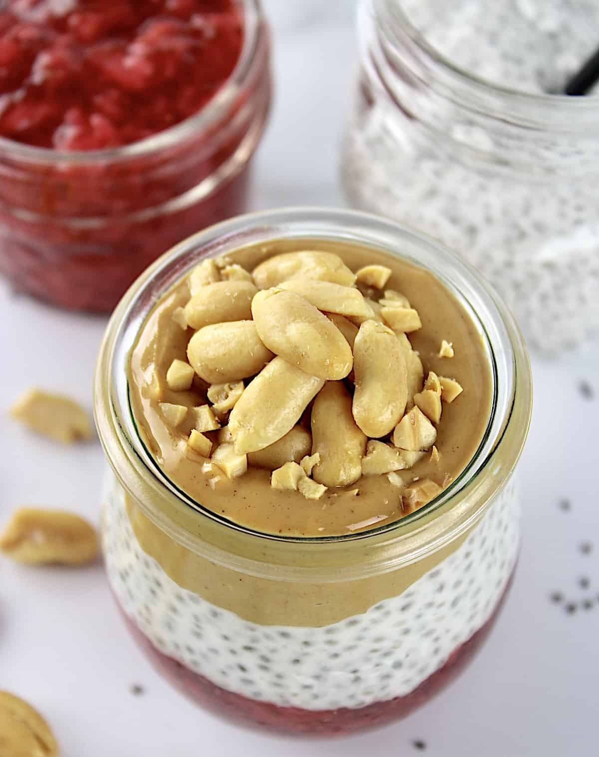 overhead view of Peanut butter and Jelly Chia Pudding in glass jar with chopped peanuts on top