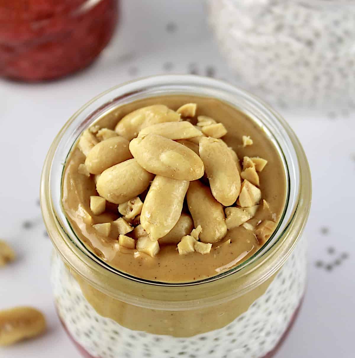overhead view of Peanut butter and Jelly Chia Pudding in glass jar with chopped peanuts on top