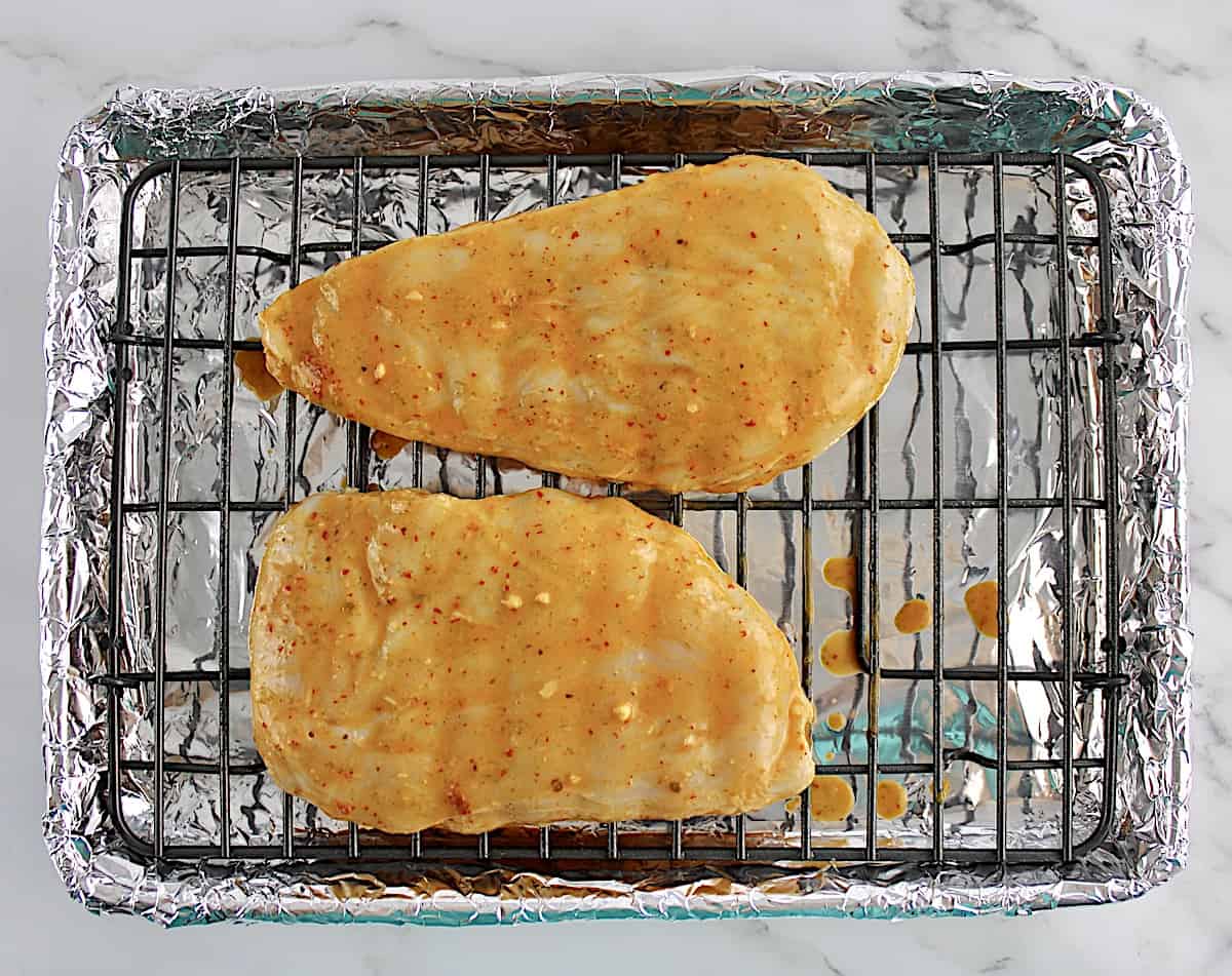 2 marinated chicken breasts on baking rack uncooked