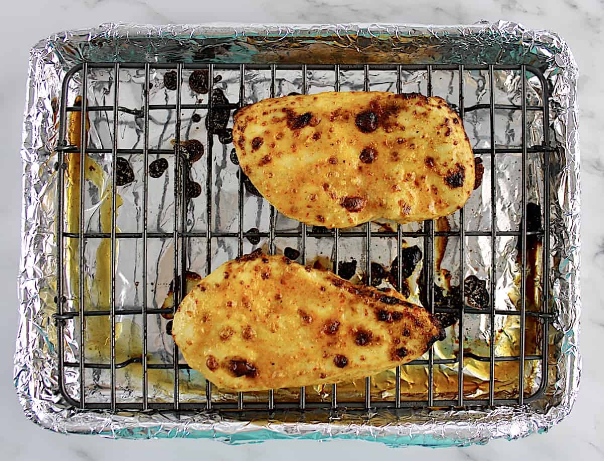 2 cooked chicken breasts on baking rack
