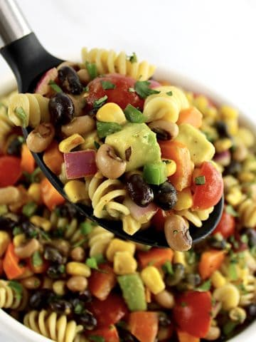 Cowboy Caviar Pasta Salad being held up by black serving spoon