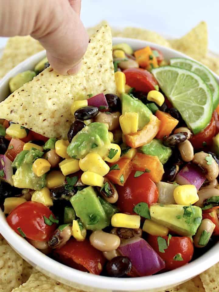Cowboy Caviar inn white bowl with tortilla chip being dipped in