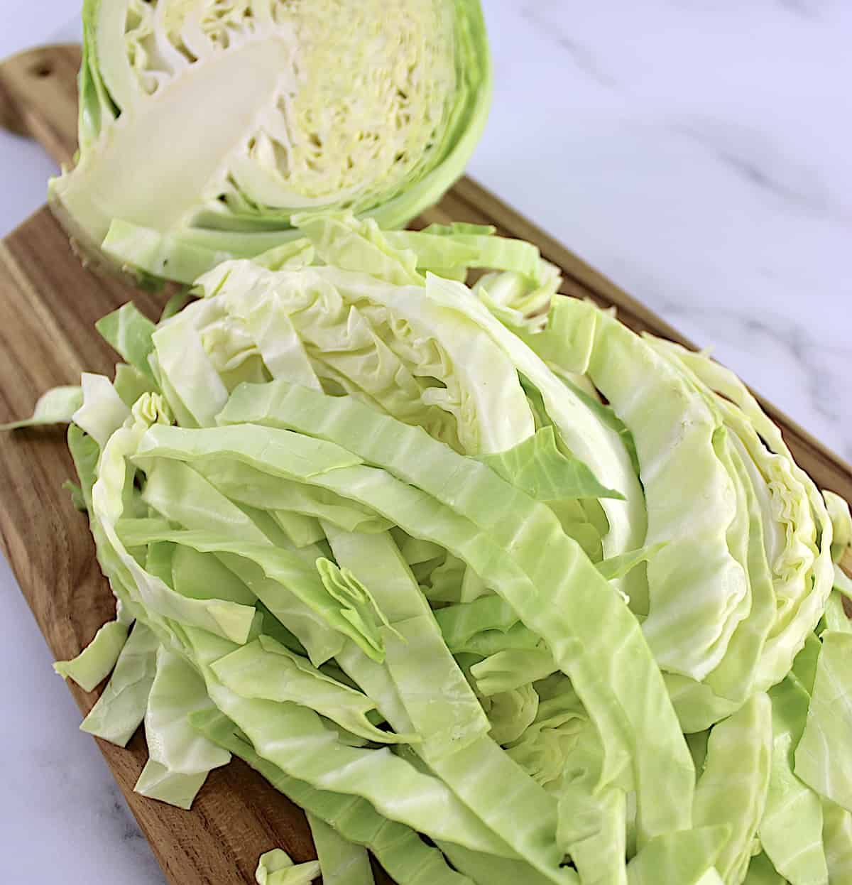 shredded cabbage on cutting board with half head in back