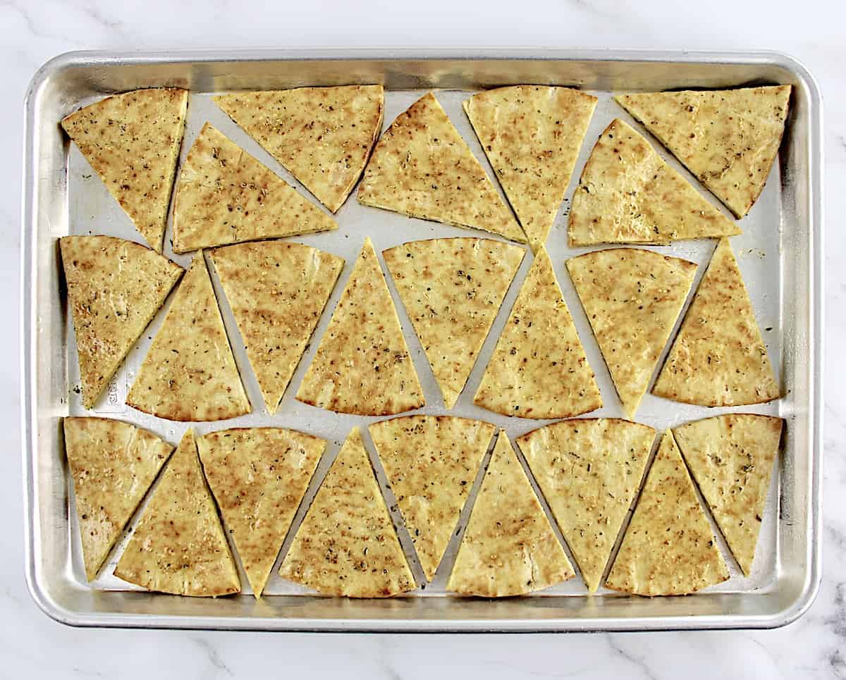 unbaked pita triangles with dried herbs and olive oil on baking sheet