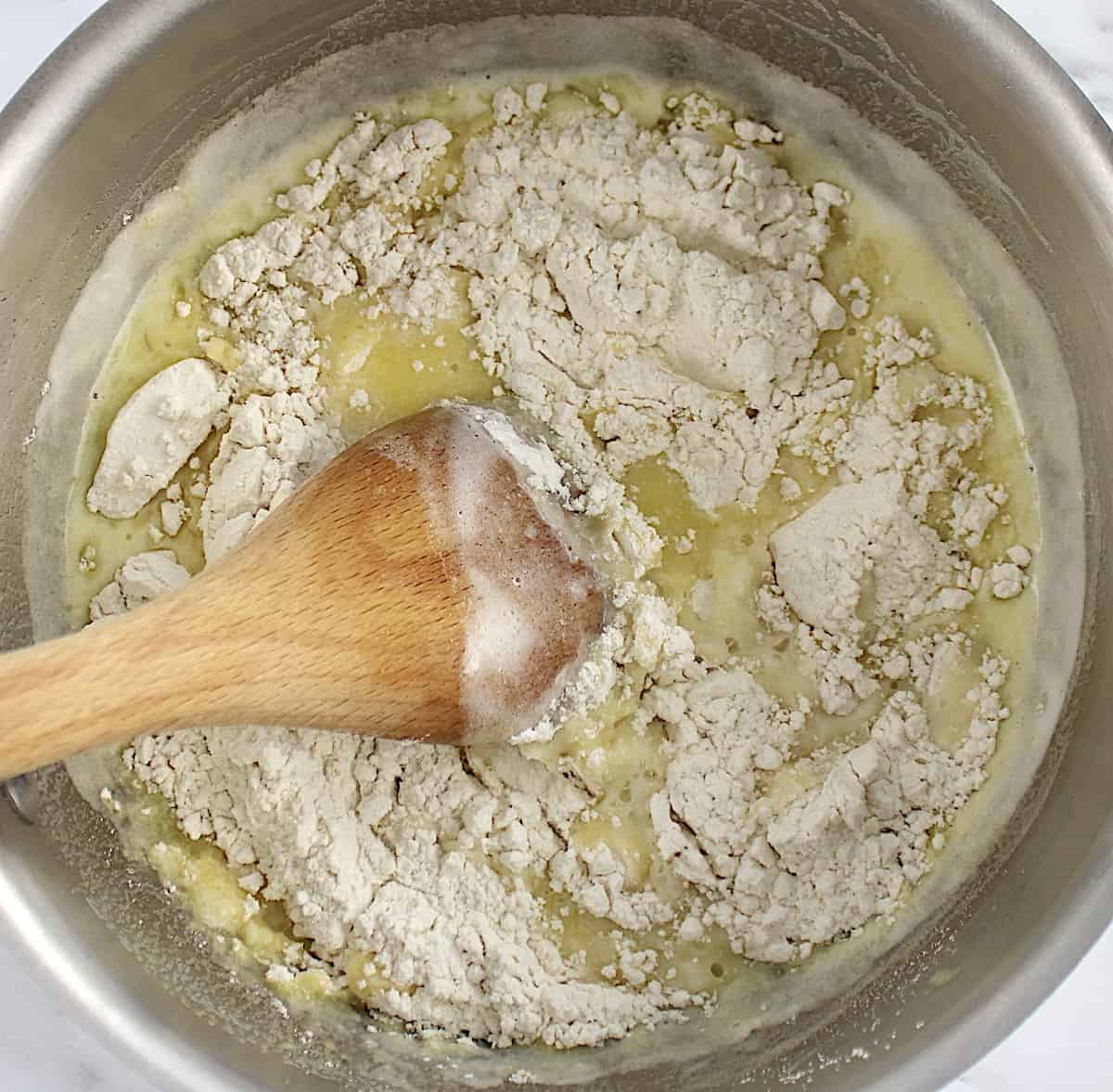 cream puff dough batter in saucepan with wooden spoon