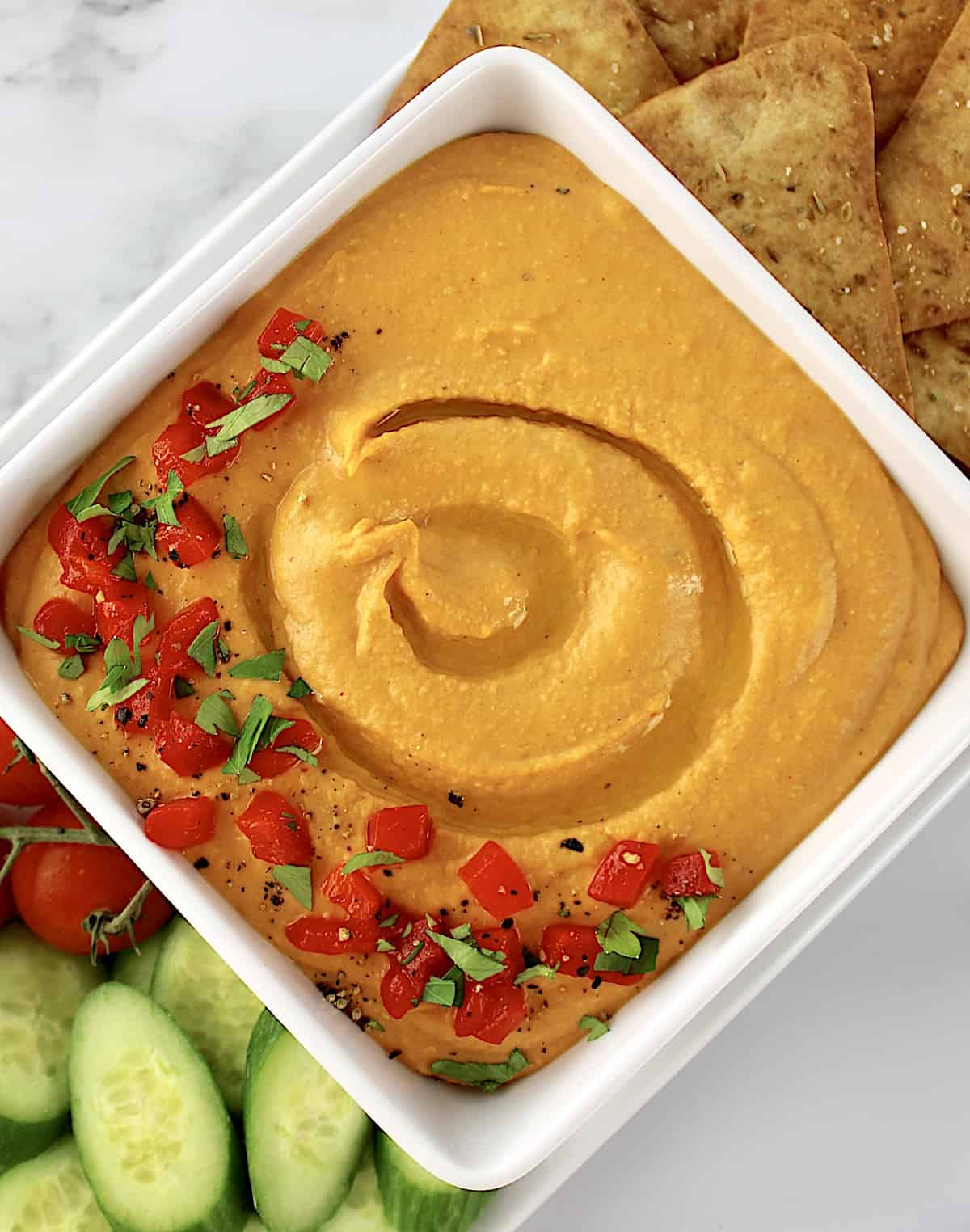 overhead closeup view of Roasted Red Pepper Hummus in white square bowl