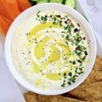 Whipped Feta Dip in white bowl with pita chips, cucumber. slices and orange pepper strips on side