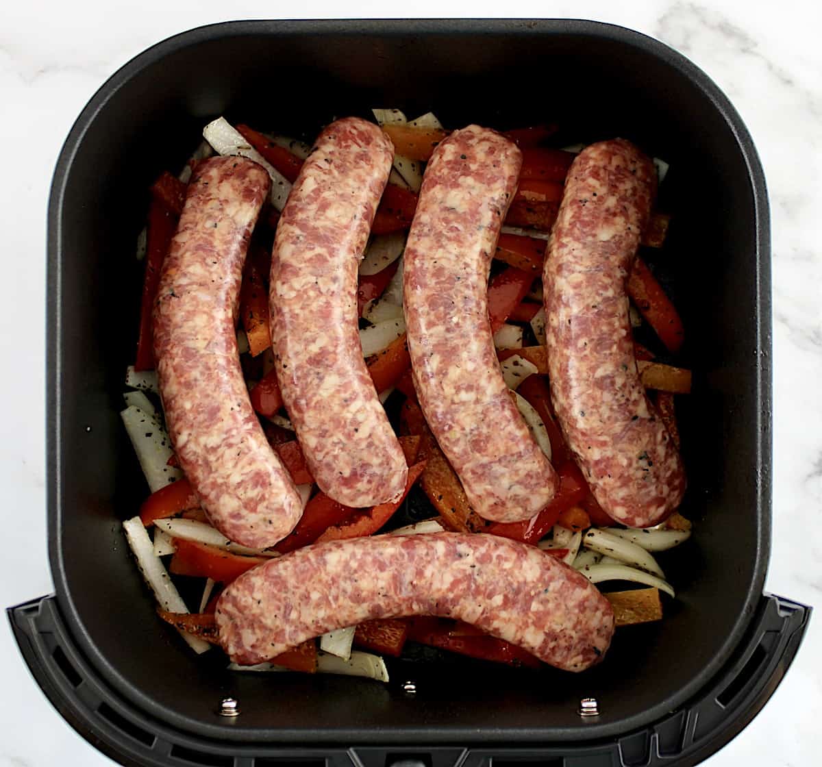 raw Italian Sausage and Peppers in air fryer basket