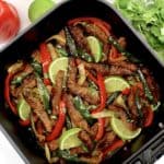 Air Fryer Steak Fajitas i air fryer basket with veggies in background