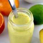 Citrus Vinaigrette in glass jar with spoon and fruit in background