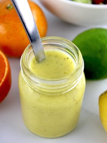 Citrus Vinaigrette in glass jar with spoon and fruit in background