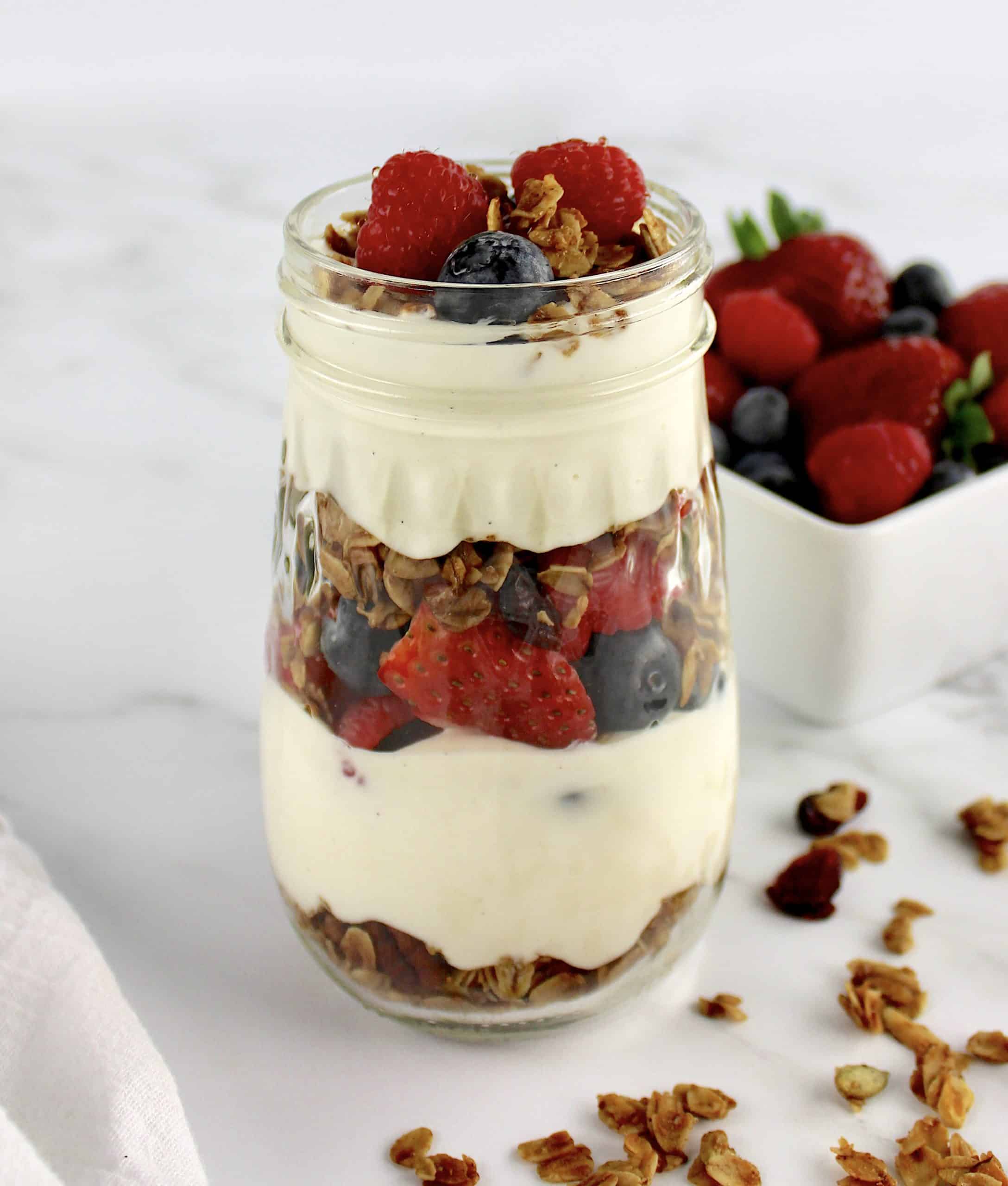 side view of Easy Granola Parfait with berries in white bowl in background