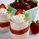 Easy Strawberry Mousse in 2 glass jars with whip cream and strawberry slice on top