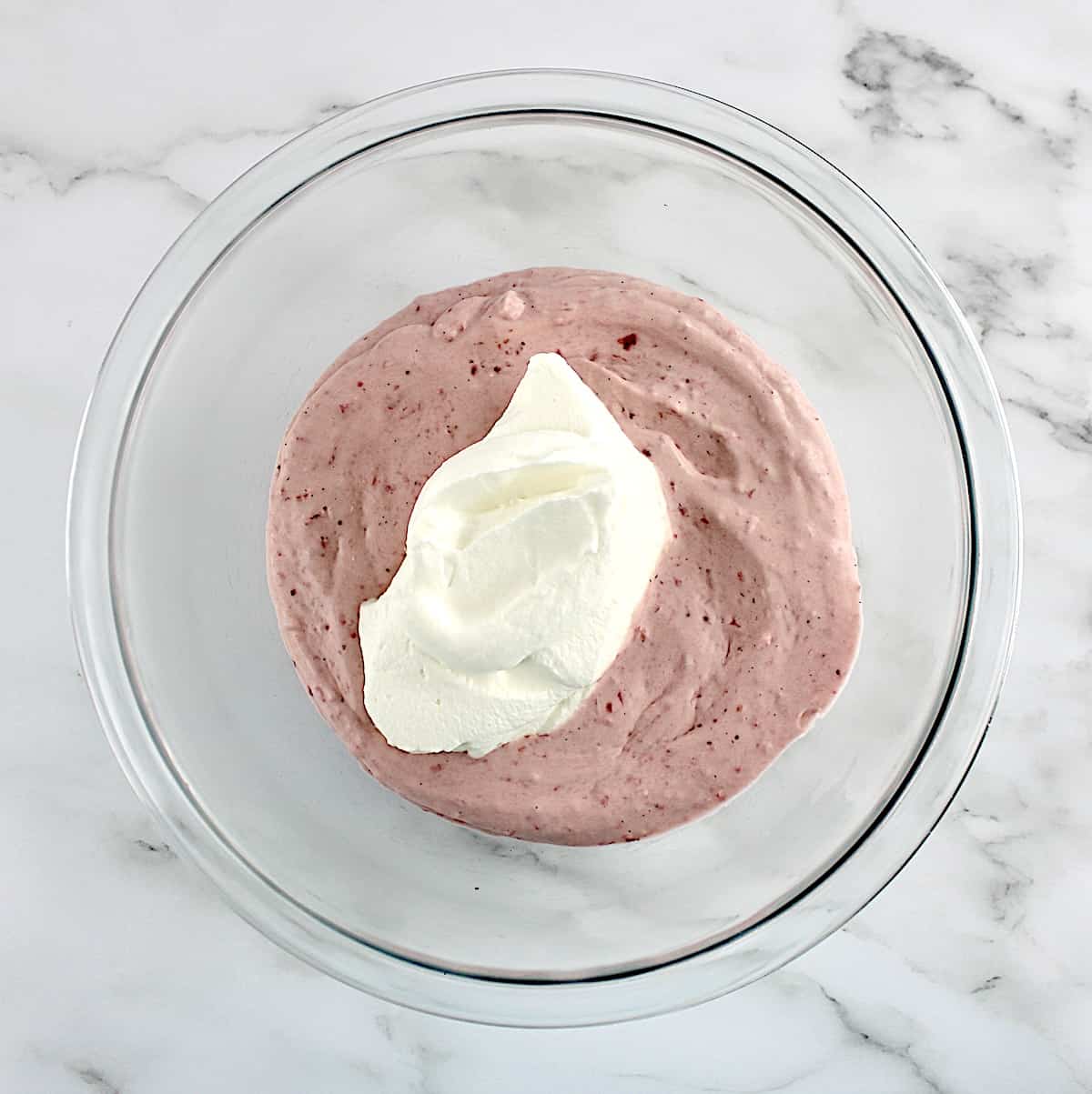 whip cream dollop over strawberry mousse in glass bowl