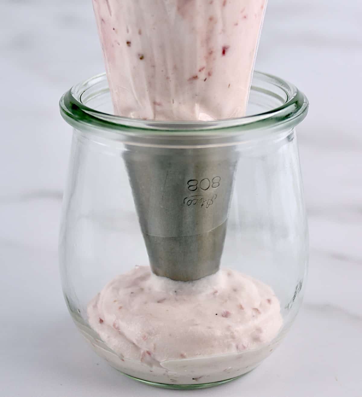 Easy Strawberry Mousse being piped into glass jar