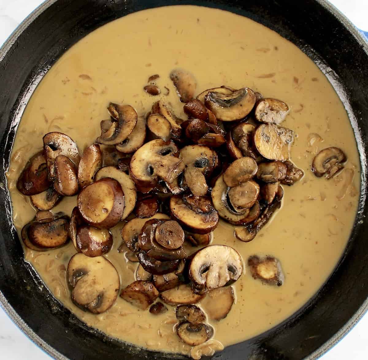 sauteed mushrooms in sauce cooking in skillet