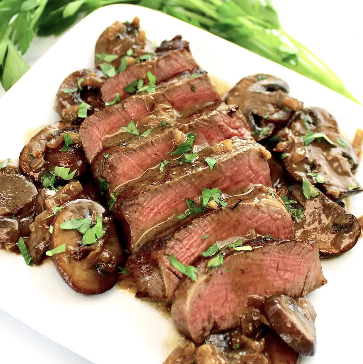 closeup of sliced Filet Mignon with Mushroom Sauce on white plate