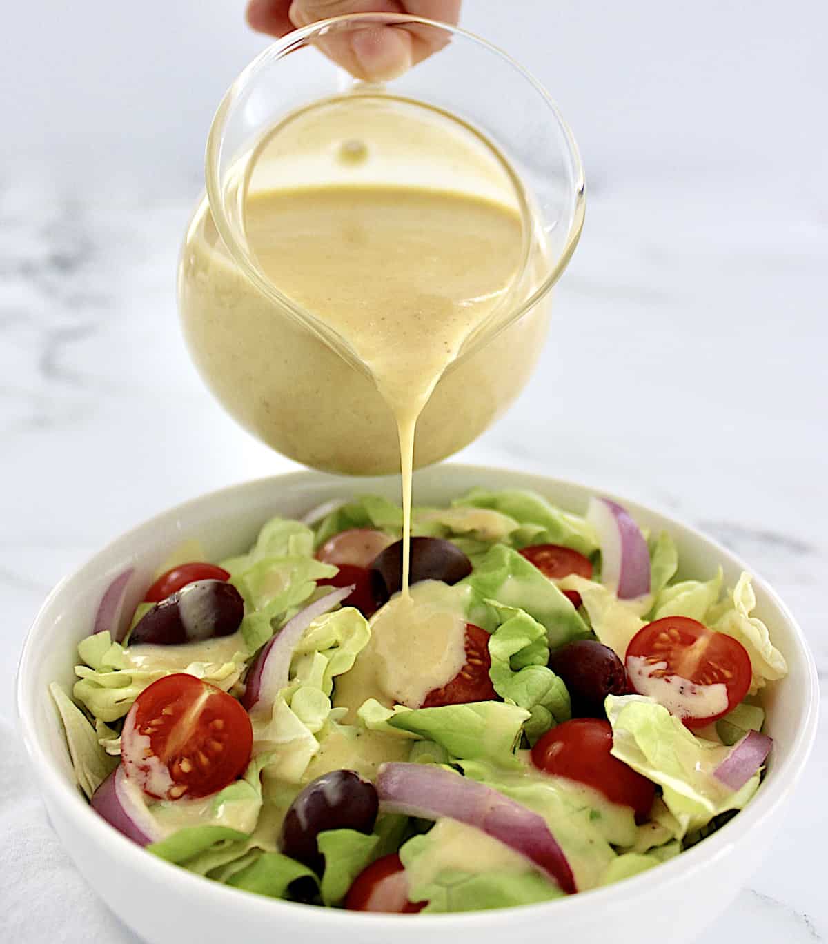 Honey Mustard Dressing being poured over salad in white bowl