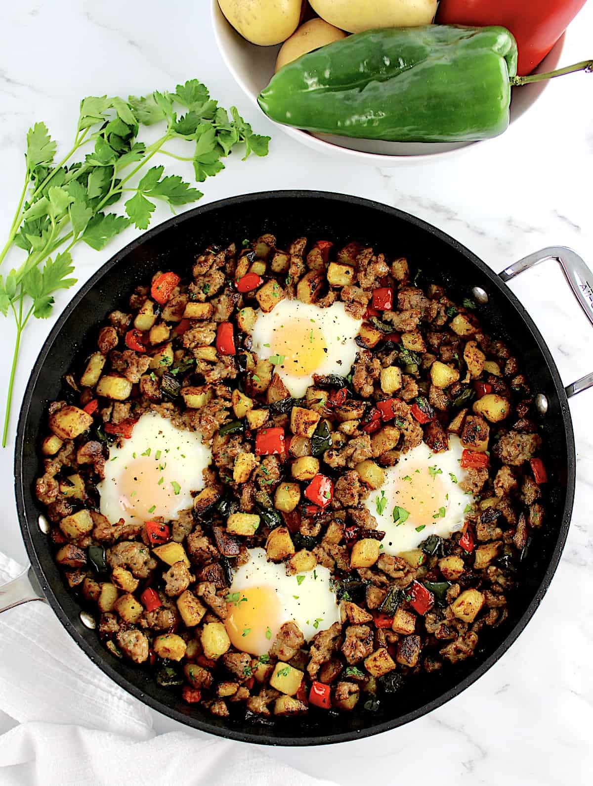 Italian Sausage and Peppers Hash in skillet with 4 eggs