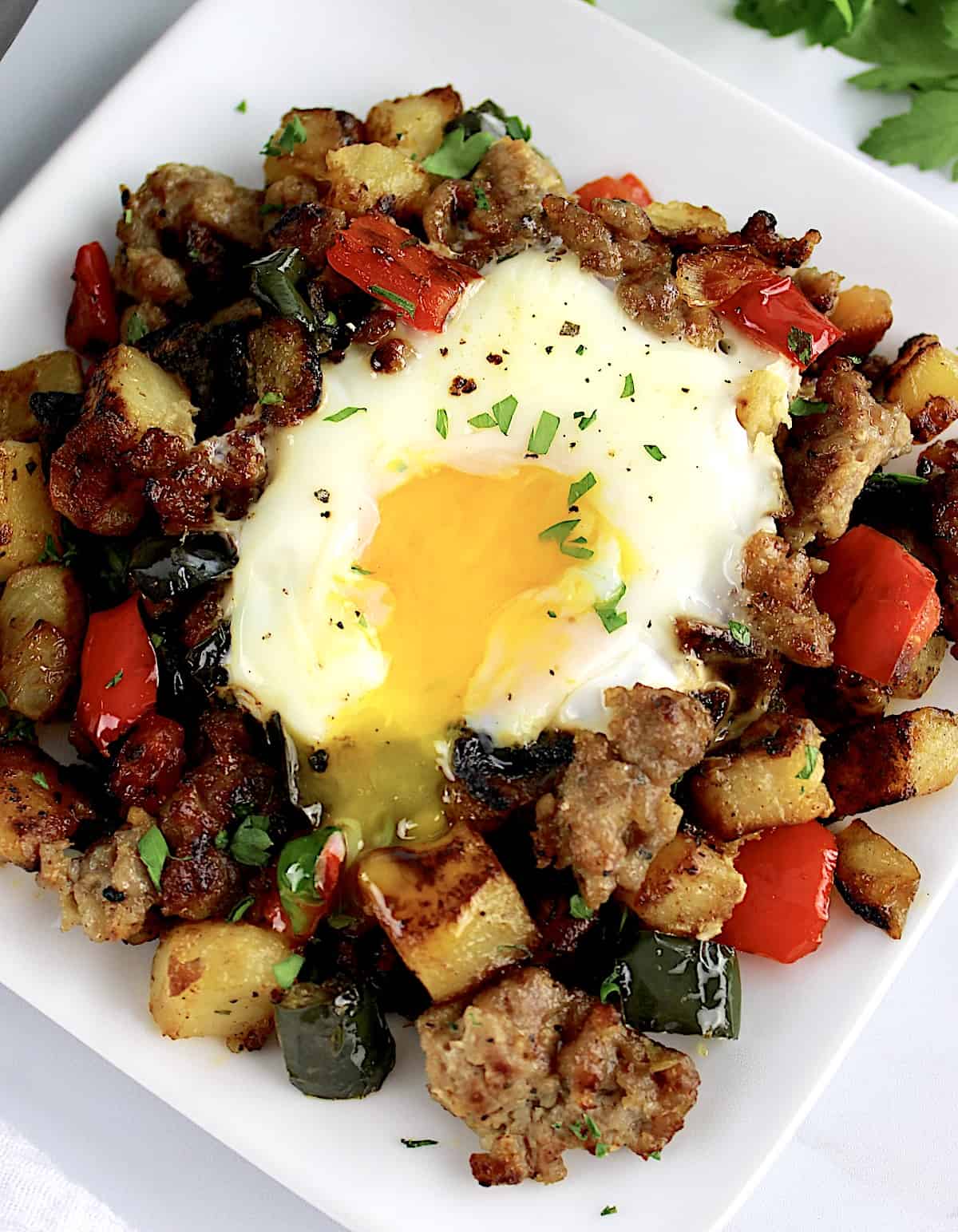 closeup of runny egg over Italian Sausage and Peppers Hash