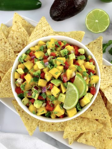 Mango Salsa in white bowl with tortilla chips around