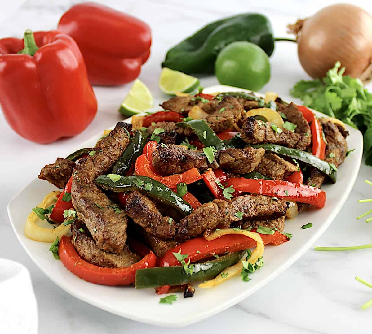 Air Fryer Steak Fajitas on white plate with peppers in background