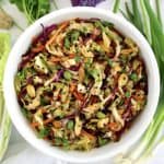 Asian Cabbage Slaw in white bowl with cabbage and scallions on side
