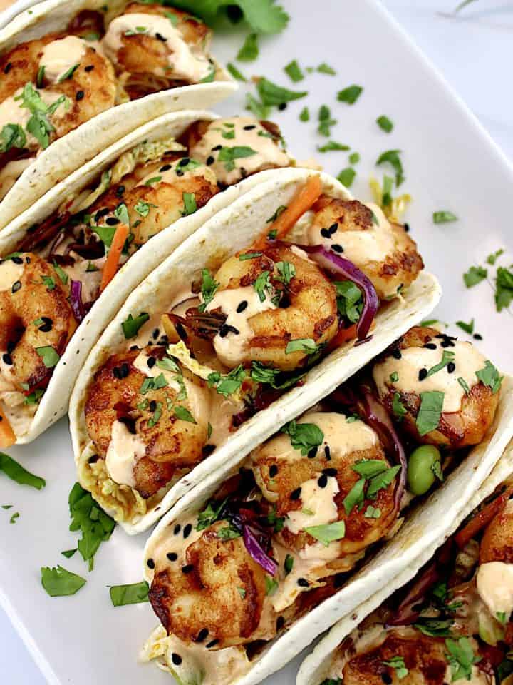 overhead view of Asian Shrimp Tacos lined up on white plate